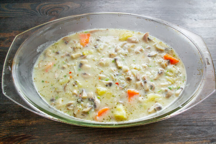 Pouring the Creamy Mushroom Sauce Over the Casserole Pouring a creamy mushroom sauce over the turkey and vegetable mixture in a casserole dish.