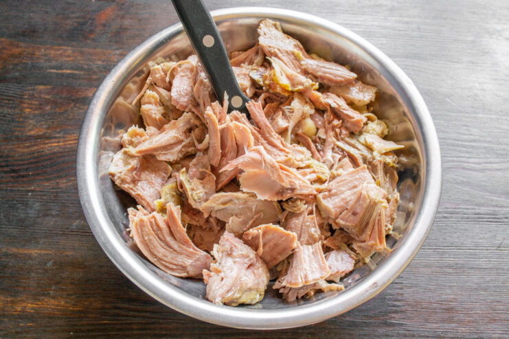Preparing the Cooked Turkey Meat for the Casserole Hands separating cooked turkey meat from the bones.