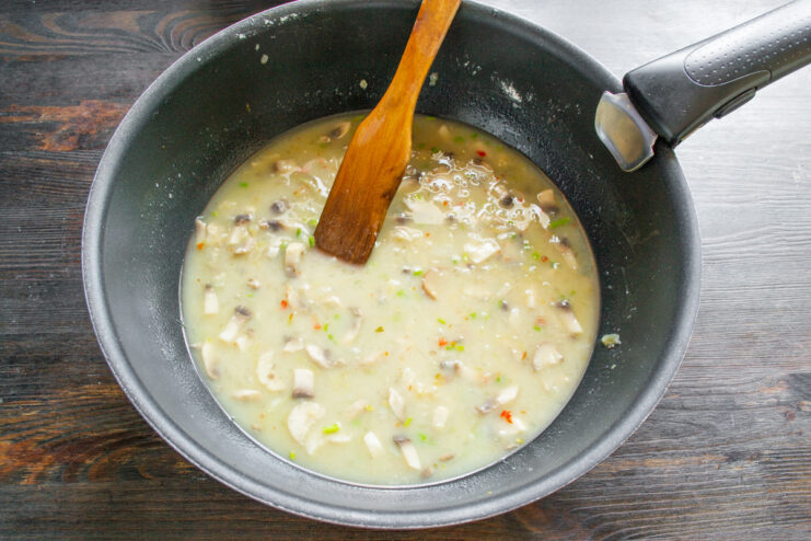 Creating a Creamy Sauce with Vegetable Broth Pouring broth into a pan with mushrooms and onions to create a sauce.