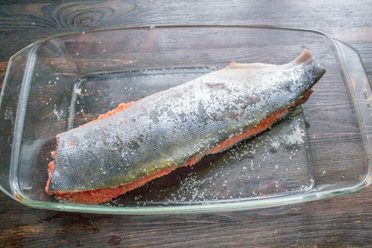 Stacking the Salmon Fillets for Curing Two seasoned pink salmon fillets stacked on top of each other in a glass dish.