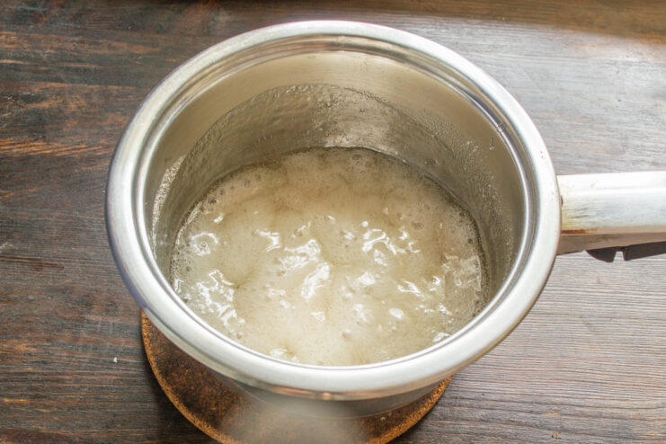 Cooking the sugar syrup to the soft-ball stage A candy thermometer in a saucepan of boiling sugar syrup, showing the temperature.