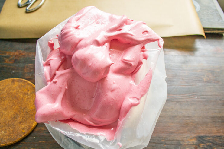 Filling the piping bag with the finished zefir mixture A spatula transferring the thick, glossy pink zefir mixture into a piping bag.