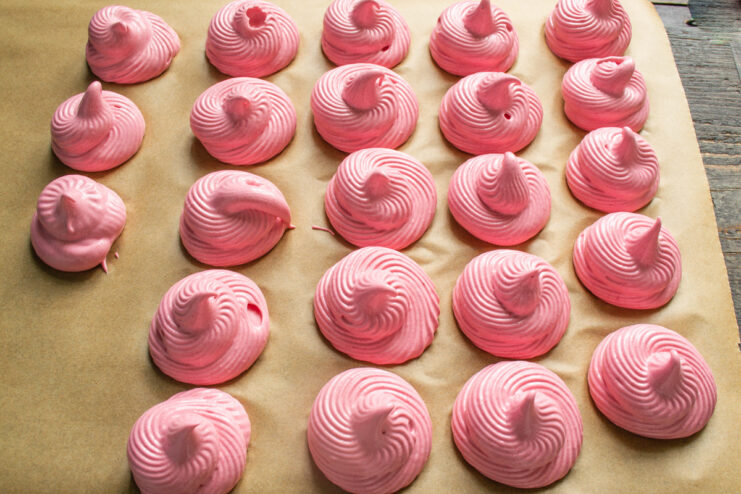 Piping individual zefir swirls Piping beautiful pink zefir swirls onto a sheet of parchment paper.