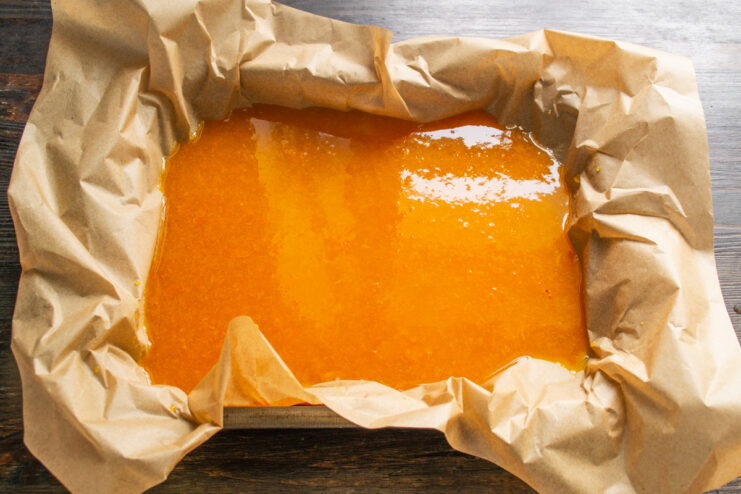 Pouring Jelly into the Mold Pouring apricot puree into a parchment-lined baking dish