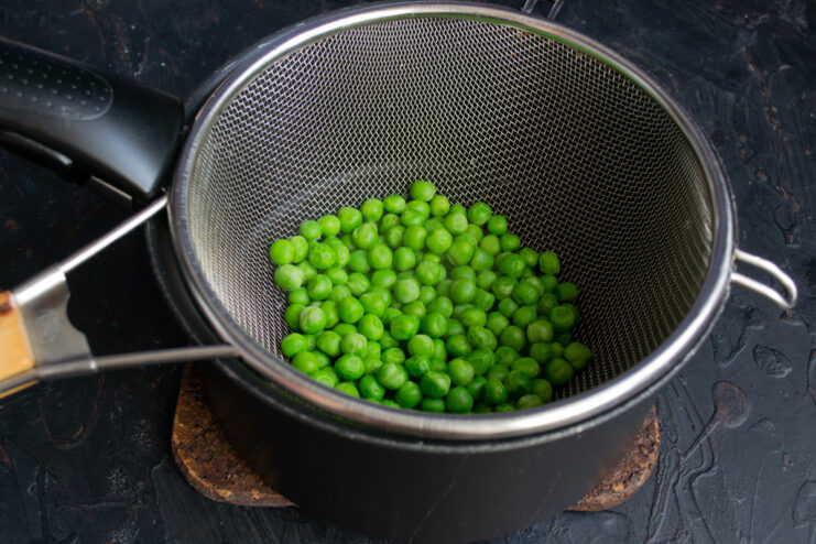 Blanching The Peas Blanched green peas draining in a fine-mesh sieve