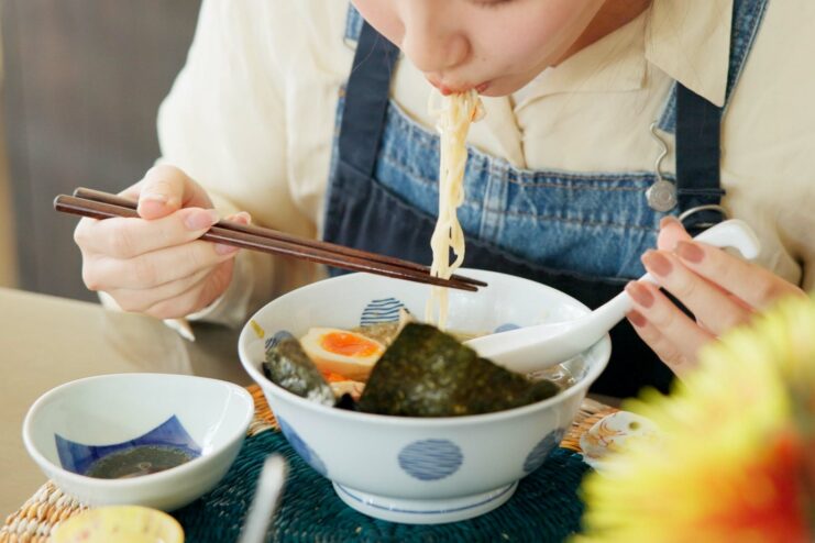 Eating ramen correctly Person eating ramen with chopsticks and slurping noodles in traditional Japanese style
