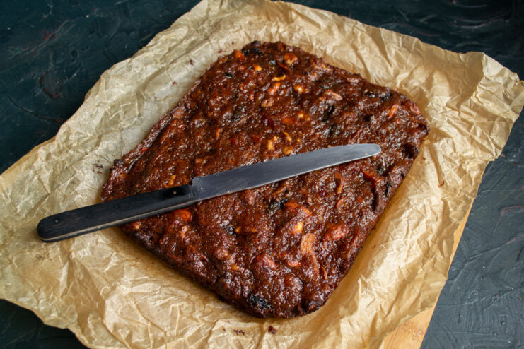 Cooled cake A whole panforte sitting on parchment paper next to a knife
