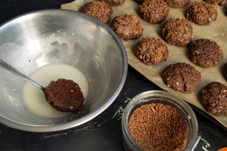 Decorating the Cookies Dipping half of a chocolate cookie into white glaze and chocolate sprinkles