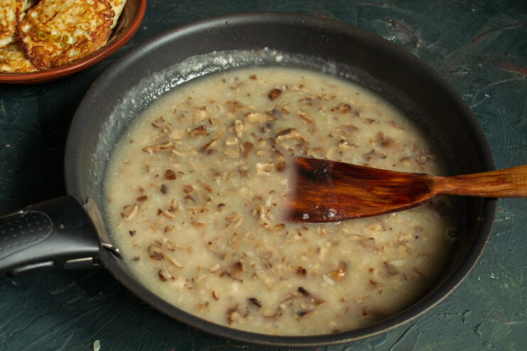 Whisking in the broth Pouring mushroom broth into a skillet with the mushroom mixture