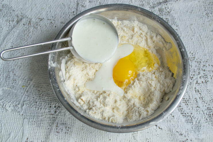 Adding the Wet Ingredients Pouring kefir and adding an egg to the flour mixture to make dough.
