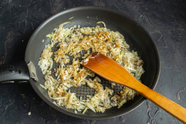 Enhancing the filling with spices Adding ground coriander and cumin to the sautéed onions in the skillet