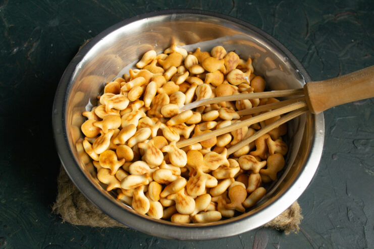 Adding the tiny crackers Pouring tiny sweet fish crackers into the bowl of sour cream mixture