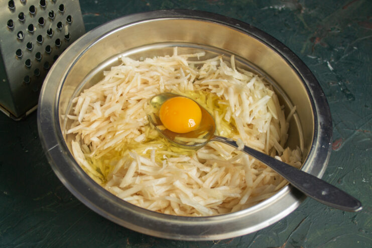 Adding the binder Adding a raw egg to the grated vegetable mixture
