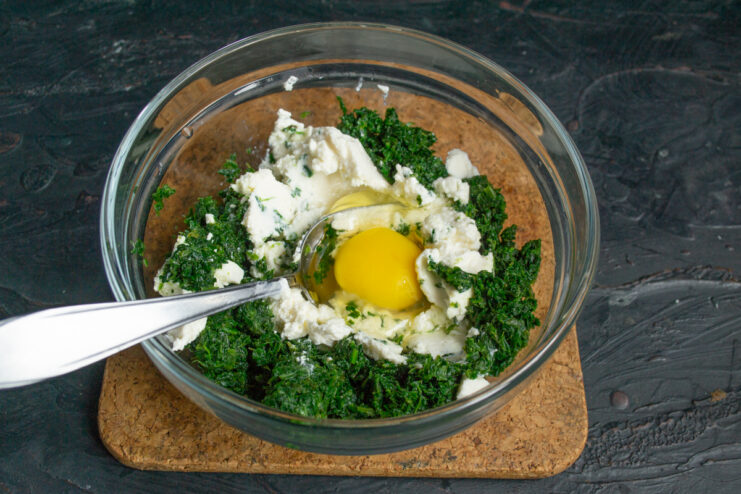 Adding a cracked egg into the spinach and cheese mixture