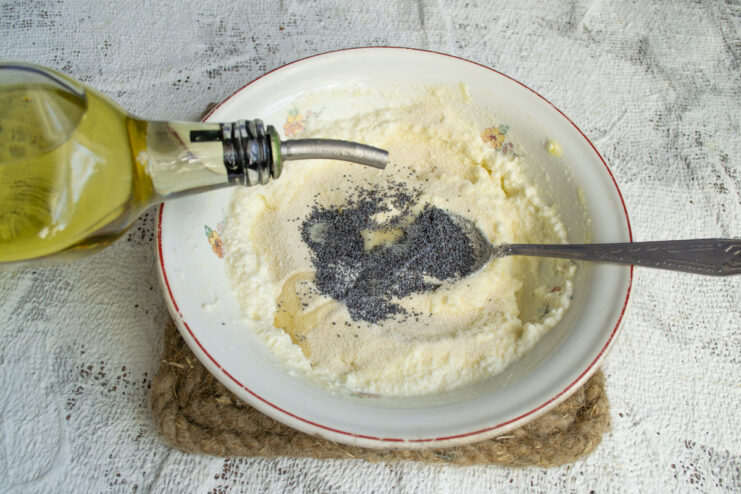 Pouring oil into the dough Adding a spoonful of oil to the cheese dough