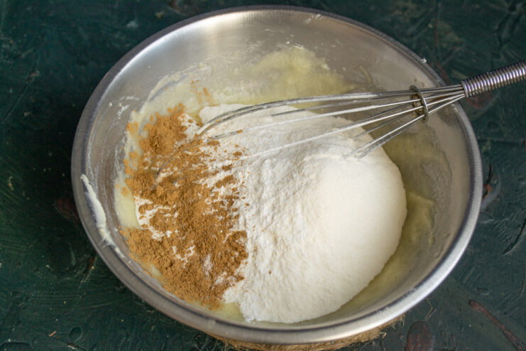 Adding dry ingredients Pouring flour and ground cinnamon into the bowl of wet ingredients.