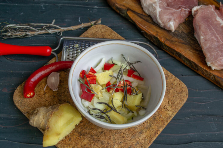 Spices in the Marinade Adding sliced chili and rosemary leaves to onion and ginger.