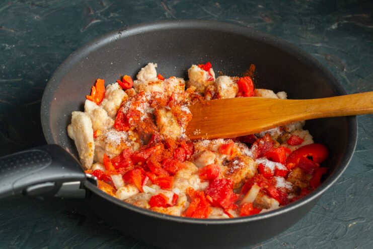 Spices And Tomatoes Mixing fresh tomatoes and ground paprika into the chicken skillet