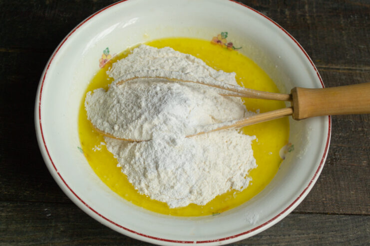 Combining dry and wet ingredients Adding sifted flour with baking powder into the batter