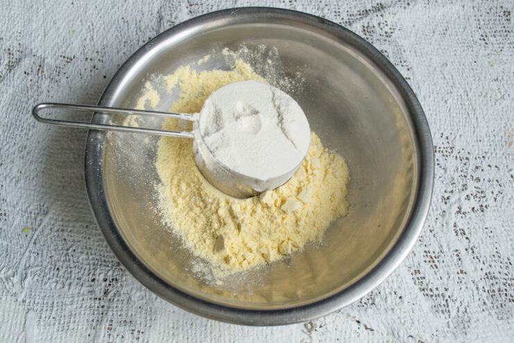 Mixing the Flours Pouring all-purpose flour into a bowl of cornmeal.
