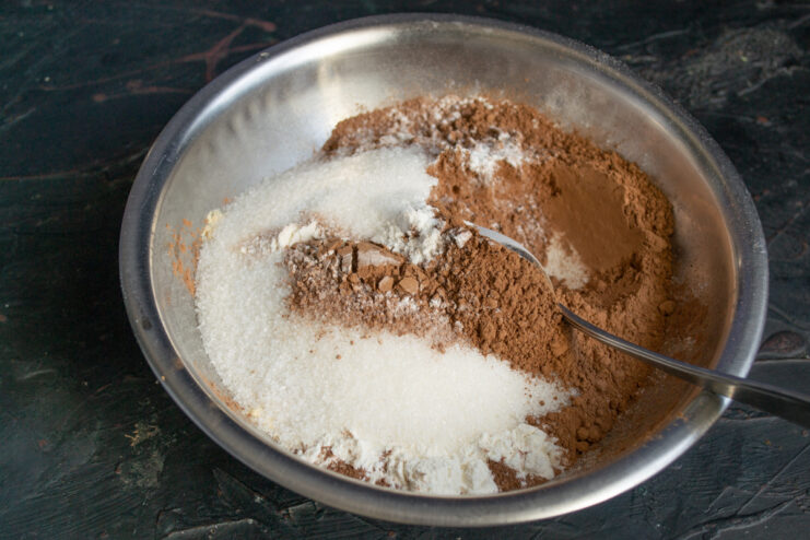 Adding the Sugar Pouring sugar into a bowl with dry chocolate dough ingredients