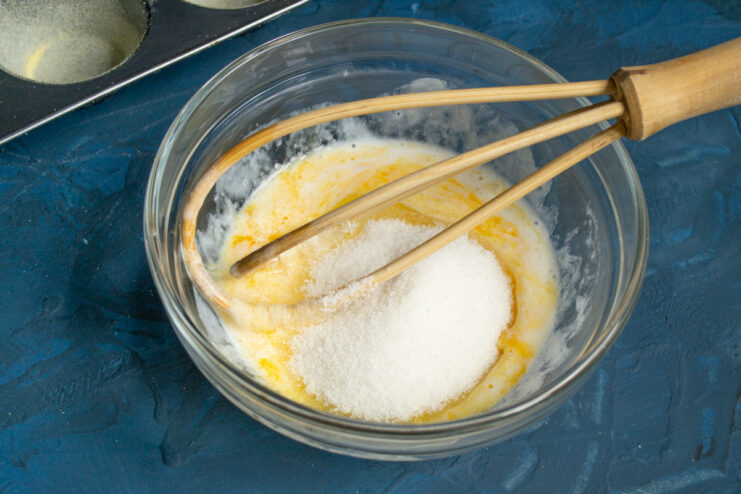 Adding sugar Adding granulated sugar to the egg and yogurt mixture.