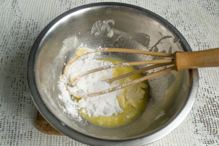 Whisking butter with powdered sugar Adding powdered sugar to softened butter in a bowl