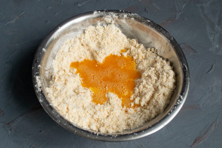 Combining wet and dry ingredients Pouring whisked salted egg into the buttery crumbs