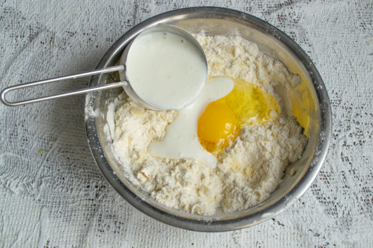 Adding wet ingredients Adding an egg and kefir to the flour mixture to form cookie dough