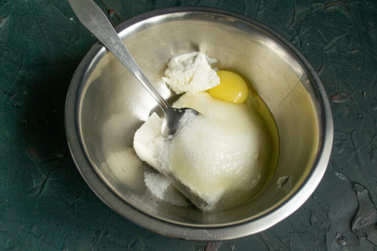 Adding a fresh egg and granulated sugar into the cheese mixture.
