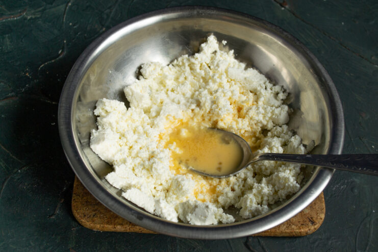 Adding egg and salt to the dough Adding a fresh egg and salt into the mashed cheese mixture