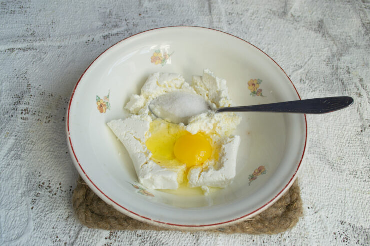 Adding egg and vanilla to the dough Cracking a fresh egg into the farmer's cheese mixture