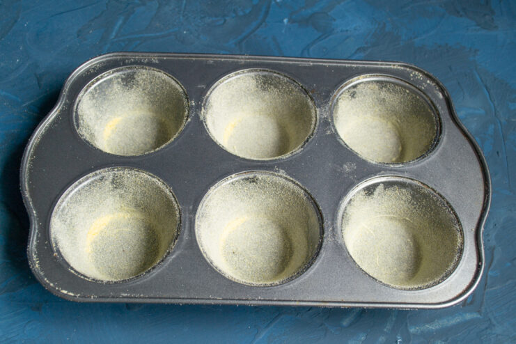Prepared muffin pan Muffin pan evenly coated with a thin layer of cornmeal.