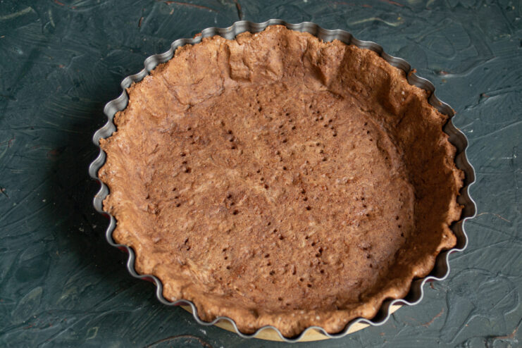 Baked Chocolate Pastry Shell A fully baked, empty chocolate pastry shell resting in a metal pan