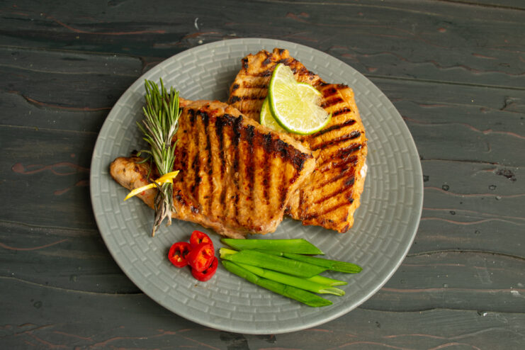 Serving the Korean-Style Pork Finished grilled pork with a vegetable garnish on a gray plate.