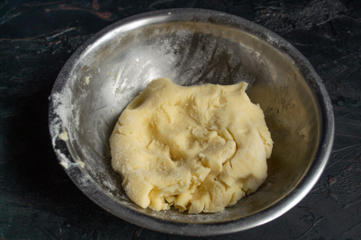 Smooth ball of kneaded shortbread dough resting in a metal mixing bowl.
