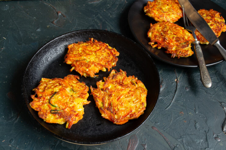 Cooked carrot fritters plated and in a skillet