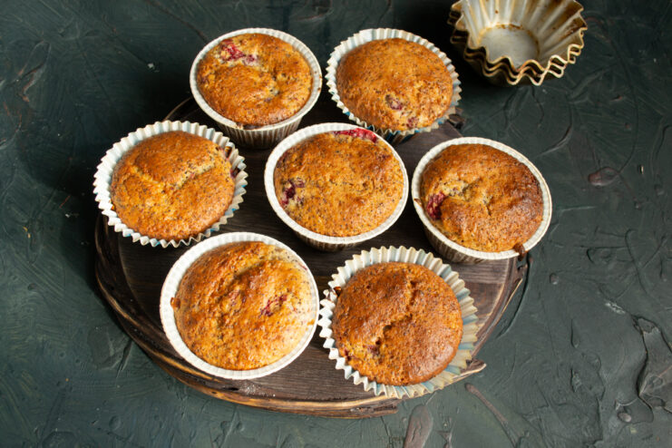 Warm baked muffins resting and cooling down on a wooden surface.