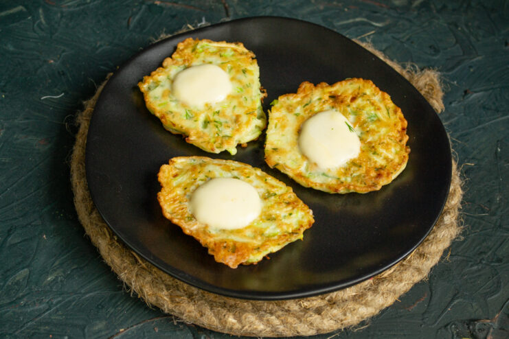 Finished Fritters Freshly fried zucchini fritters resting on a dark plate