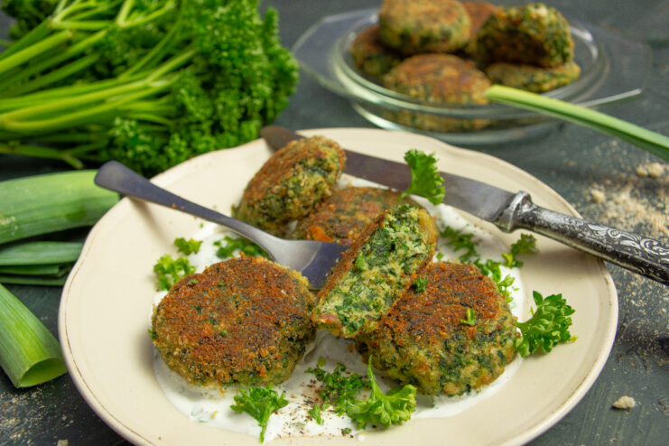 Cooked spinach and ricotta vegetable patties served on a plate with creamy sauce