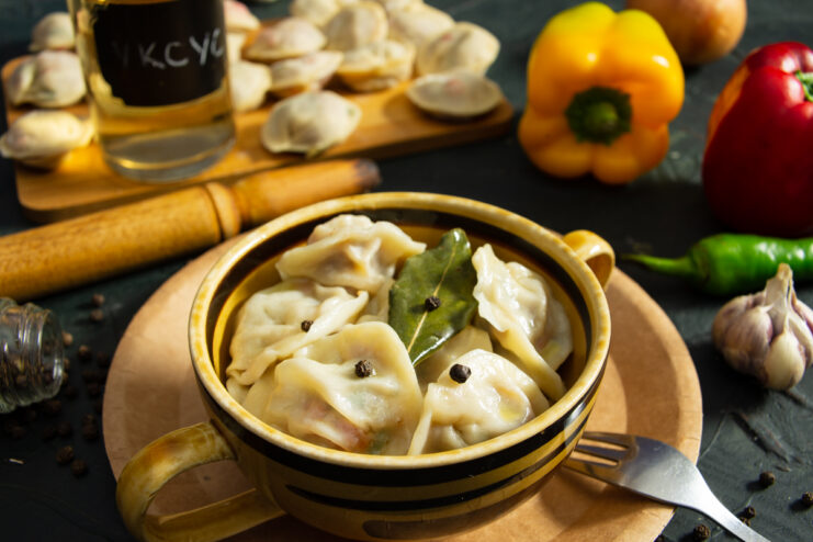 Finished beef and bell pepper pelmeni served in a deep bowl with a bay leaf