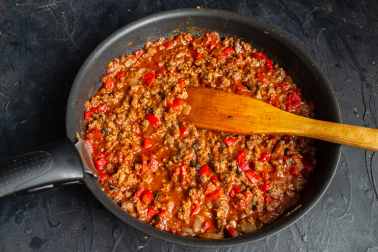 Simmering the beef sauce Thick ground beef and vegetable sauce simmering gently in a skillet.