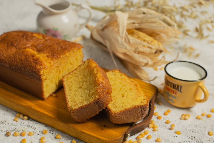 Sliced golden cornmeal cake served on a wooden cutting board.