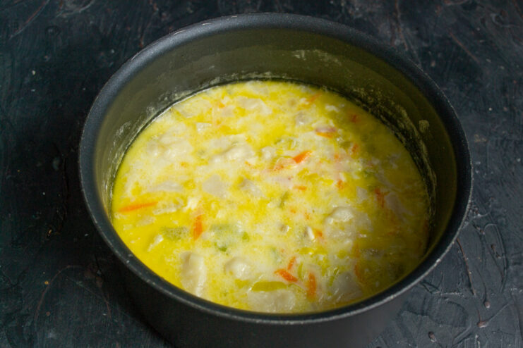 Heating the soup to a boil after adding cream Finished creamy soup gently simmering in a pot