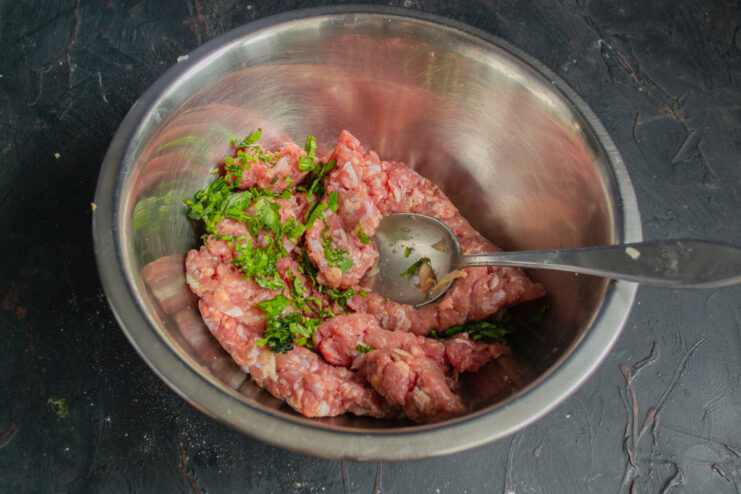 Mixing fresh cilantro with beef Ground beef mixed with freshly chopped cilantro in a bowl