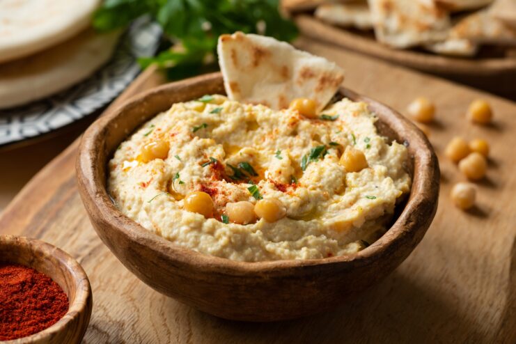 Textured Musabbaha Coarse Hummus Coarsely ground Musabbaha hummus showing whole chickpeas and rich spices in a rustic wooden bowl.