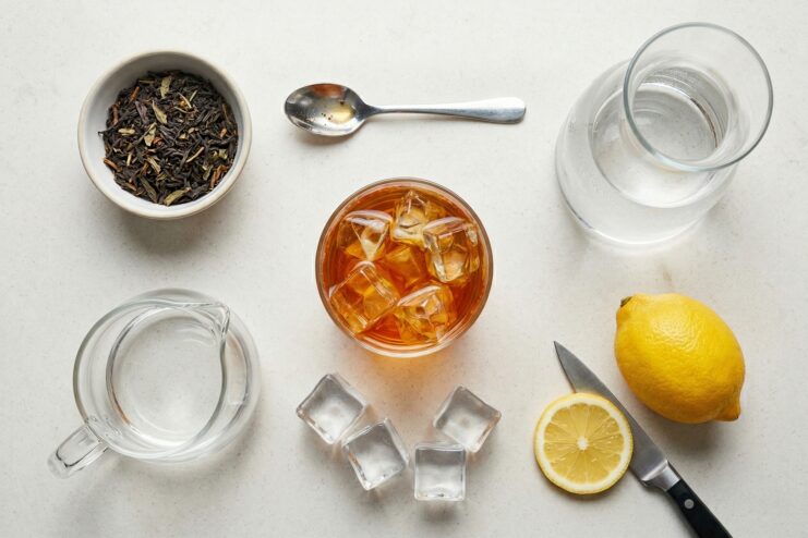 Ingredient set for perfect iced tea Iced tea ingredients including lemon wedges, ice cubes, loose tea leaves, and water against a light background