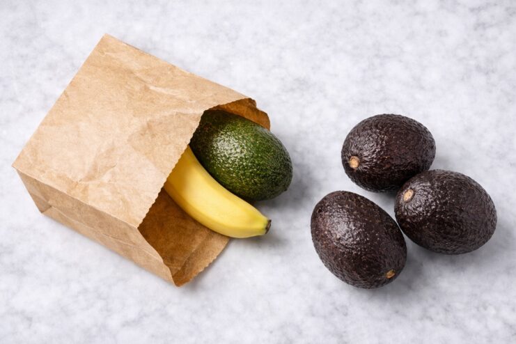 Avocado and Banana in a Paper Bag Green avocado and yellow banana sitting inside an open brown kraft paper bag