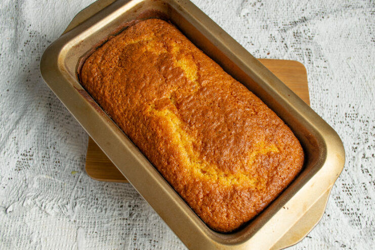 Checking for Doneness Freshly baked golden cake resting inside a loaf pan.