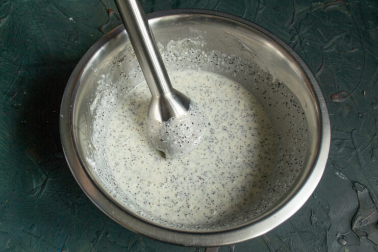 Blending the muffin batter ingredients smoothly using an immersion blender.